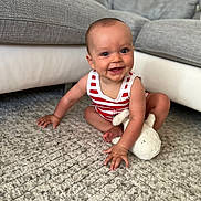 Lucien participe au concours pour gagner de l'argent avec cette photo : baby, child, smiling, indoor, carpet, plush_toy, striped_clothing, couch, furniture, happy, cute, sitting, infant, person, young_child, home, floor, playful, bright, portrait