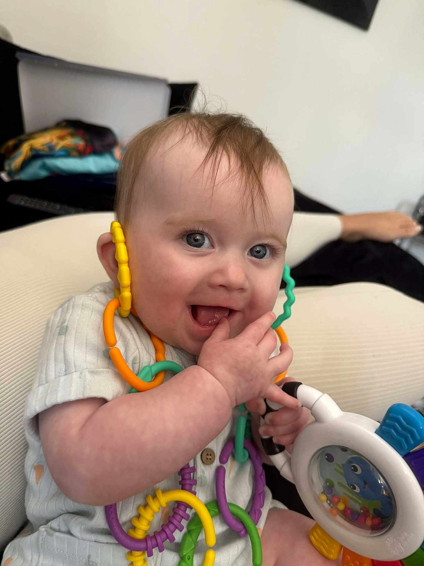 Aiyla joined the competition — help win amazing prizes! baby, child, toy, colorful, playful, smiling, happy, indoor, plastic_rings, hand, face, sitting, clothing, furniture, blue_eyes, cute, infant, person, expression, young