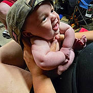 Olyvers is registered to the contest to win money with this photo: baby, child, smiling, hat, camo, cap, indoor, person, holding, hands, legs, toes, furniture, chair, bag, casual, happy, cute, portrait, infant