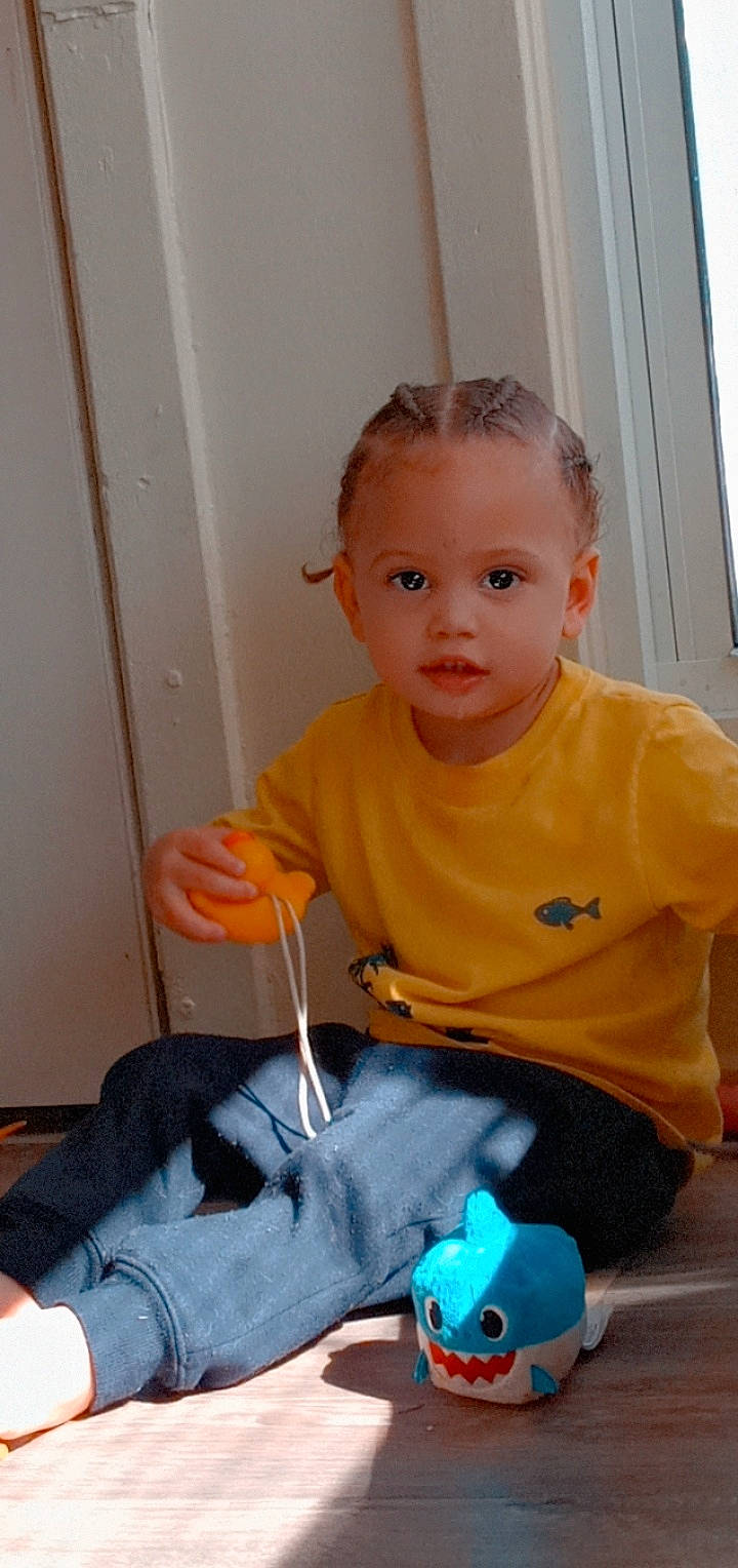 Jordan is registered to the contest to win money with this photo: baby, baby_products, baby_toddler_clothing, chair, child, electric_blue, eye, flooring, fun, head, nose, person, play, room, sitting, skin, stuffed_toy, t_shirt, thumb, toddler