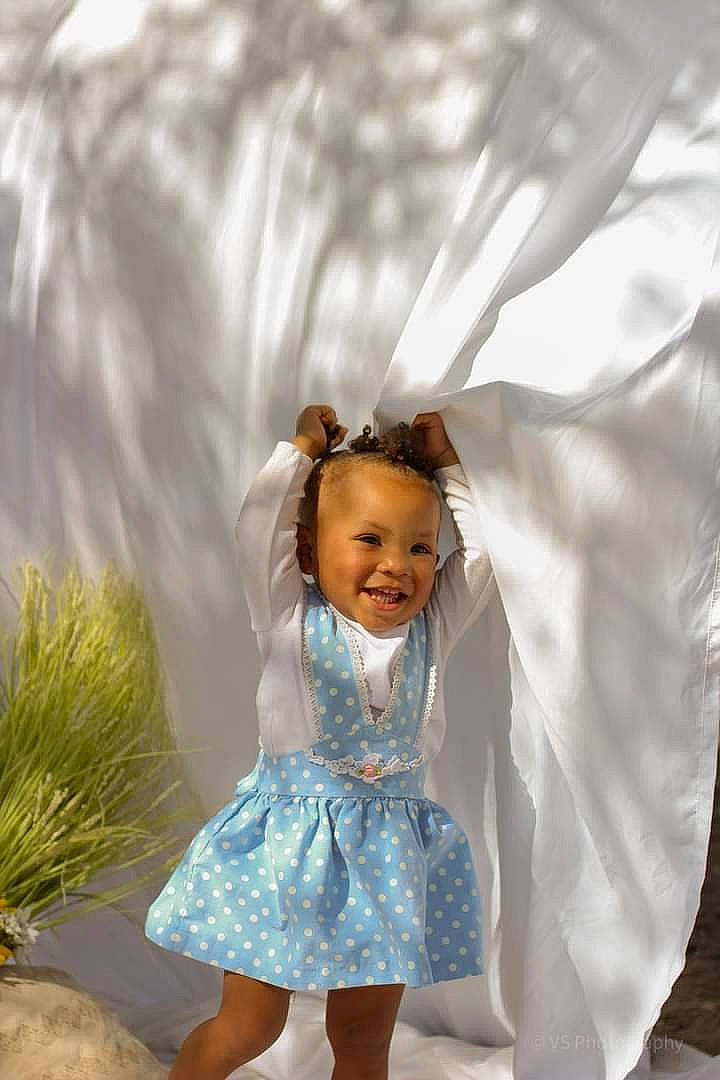 Kamiyah is registered to the contest to win money with this photo: baby_toddler_clothing, day_dress, dress, eye, fashion_design, formal_wear, fun, grass, hair, happy, human_body, people_in_nature, person, plant, product, skin, sleeve, smile, textile, toddler