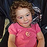 casual_clothing, child, curly_hair, cute, embroidery, expression, face, happy, hoodie, indoors, pattern, person, pink_shirt, portrait, relaxed, sitting, skin, smile, toddler, young_child