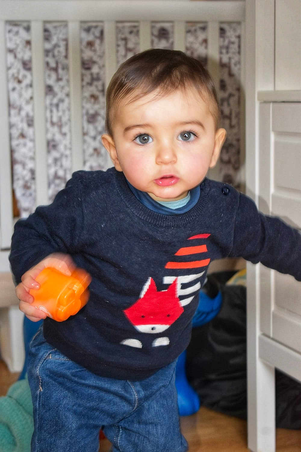 Hawes a rejoint le concours — aidez-le/la à gagner de superbes lots ! toddler, child, toy, indoor, sweater, fox, blue_eyes, curly_hair, crib, patterned_background, jeans, floor, furniture, cute, rosy_cheeks, standing, person, home, play, orange_toy
