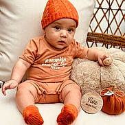 Zayvier joined the competition — help win amazing prizes! baby, infant, pumpkin_hat, orange_clothing, knitted_socks, plush_toy, teddy_bear, wooden_marker, five_months, fabric_pumpkin, cushion, chair, cute, child, indoors, portrait, seasonal, autumn, cozy, seated