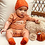 baby, infant, pumpkin_hat, orange_clothing, knitted_socks, plush_toy, teddy_bear, wooden_marker, five_months, fabric_pumpkin, cushion, chair, cute, child, indoors, portrait, seasonal, autumn, cozy, seated