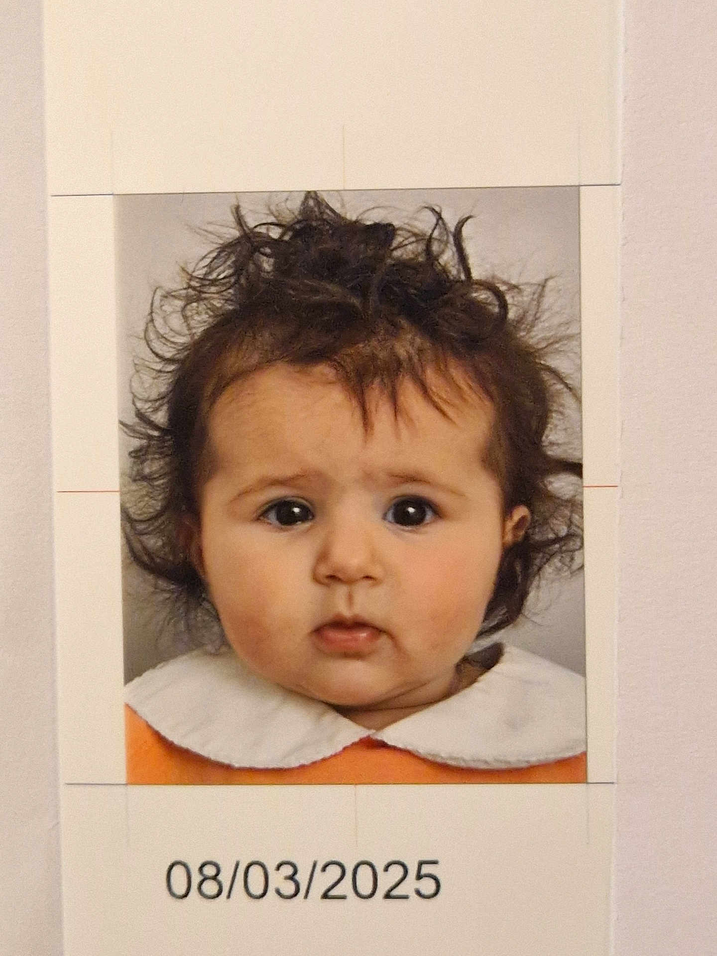 Yéva a rejoint le concours — aidez-le/la à gagner de superbes lots ! baby, portrait, child, face, hair, curly_hair, expression, clothing, white_collar, orange_outfit, studio_lighting, photo_print, date_stamp, indoor, headshot, young_child, innocent_look, closeup, person, photograph