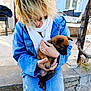 puppy, dog, person, denim_jacket, scarf, outdoor, sunglasses, pet, holding, caring, casual, concrete, steps, tree, sunlight, jeans, blond_hair, cute, animal, affection