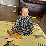 animal_print, baby, child, colorful, cute, dress, floor, furniture, home, indoor, jeans, leather_chair, person, play_mat, plush_toy, room, sitting, toy, wooden_floor, young_child