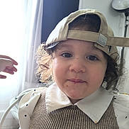 Juliette participe au concours pour gagner de l'argent avec cette photo : beige_cap, cap, child, clothing, curly_hair, curtain, cute, hand, indoor, lamp, light, messy_face, person, portrait, smile, striped_vest, toddler, white_collar, window, young_child