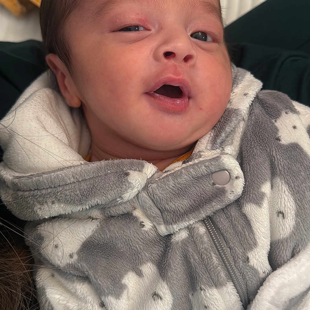 Khlil is registered to the contest to win money with this photo: baby, blanket, bunny_pattern, child, closeup, clothing, cozy, cute, expression, face, gray, indoor, infant, newborn, onesie, person, portrait, soft_fabric, warm, white