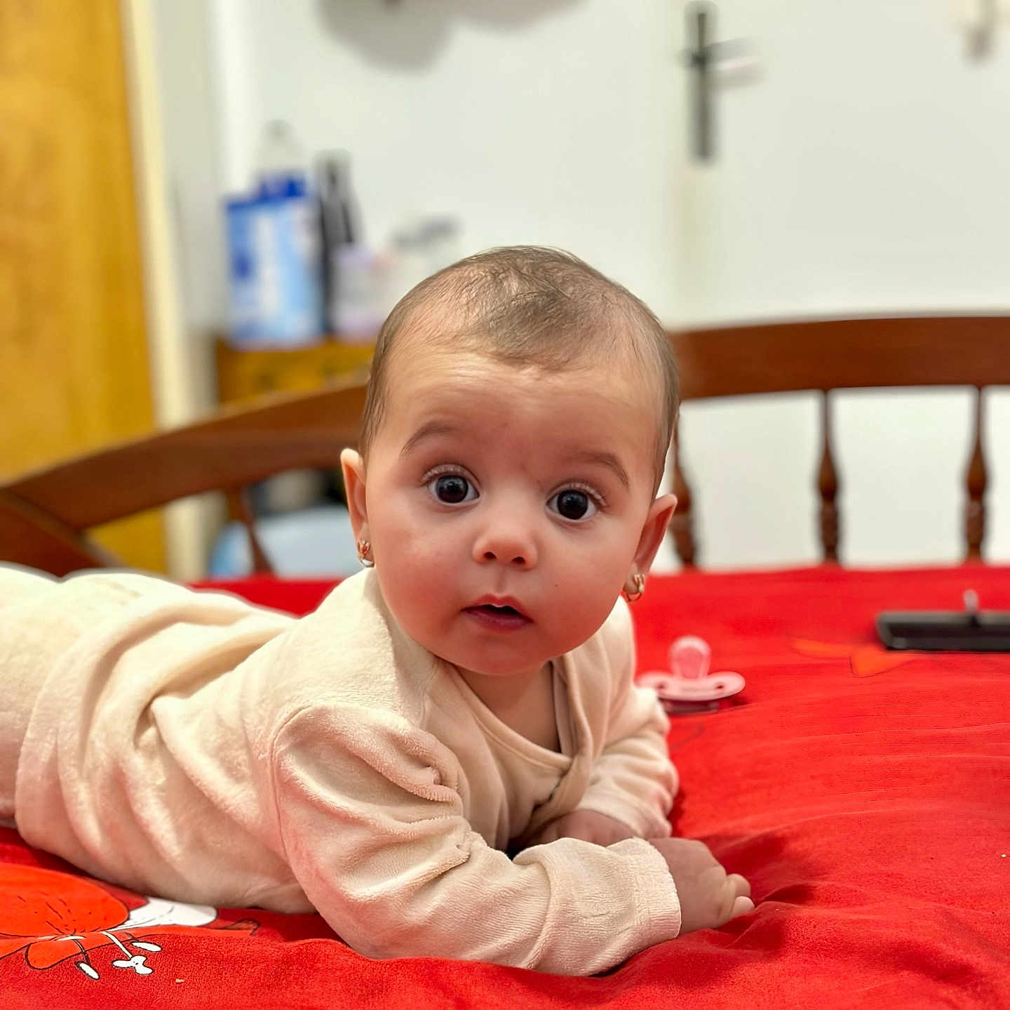 Nelissa Haziran participe au concours pour gagner de l'argent avec cette photo : baby, bed, child, clothing, curious, cute, earrings, expression, face, home, indoor, infant, lying_down, pacifier, person, portrait, red_bedspread, soft_lighting, wooden_furniture, young