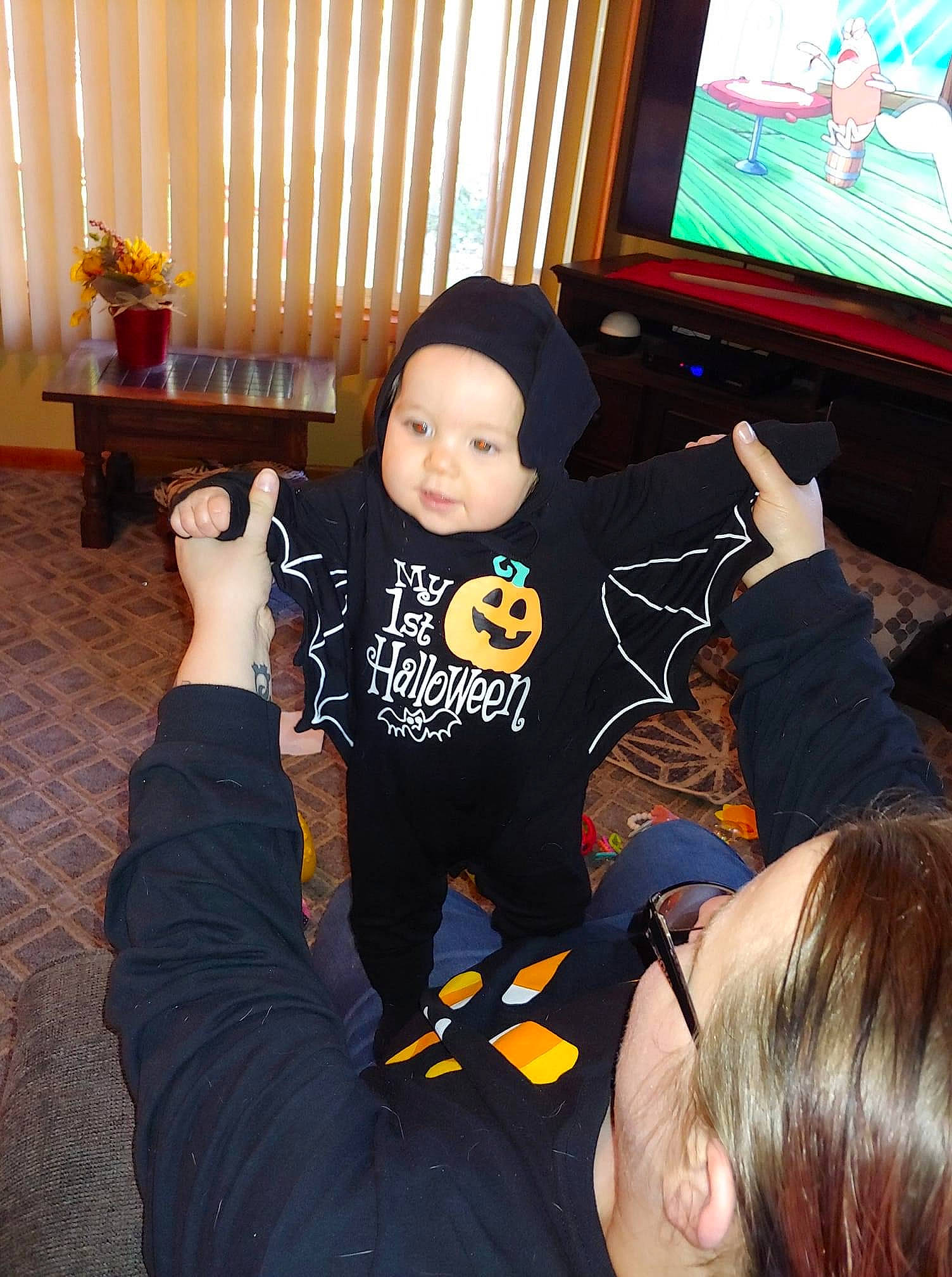 Madison is registered to the contest to win money with this photo: baby, black, black_hair, child, event, finger, fun, gesture, hand, happy, headwear, led_backlit_lcd_display, mammal, person, play, sitting, snapshot, standing, t_shirt, television