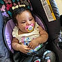 baby, pacifier, car_seat, butterfly_pattern, child, infant, clothing, hair_bow, seatbelt, patterned_pants, cute, comfort, relaxed, indoors, person, young_child, sitting, closeup, portrait, colorful
