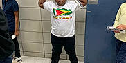 Lloyd is registered to the contest to win money with this photo: child, children, tshirt, flag, guyana, hallway, tile_wall, blue_door, floor, sneakers, black_pants, flexing, posing, casual, indoor, person, group, standing, young, school
