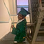 child, graduation, cap_and_gown, balloons, staircase, smile, portrait, indoors, window, railing, celebration, person, clothing, young, happy, steps, handrail, looking_back, achievement, casual