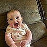 baby, infant, smile, happy, couch, furniture, indoor, child, cute, person, skin, face, hands, sitting, apparel, short_sleeve, home, relax, joy, playful