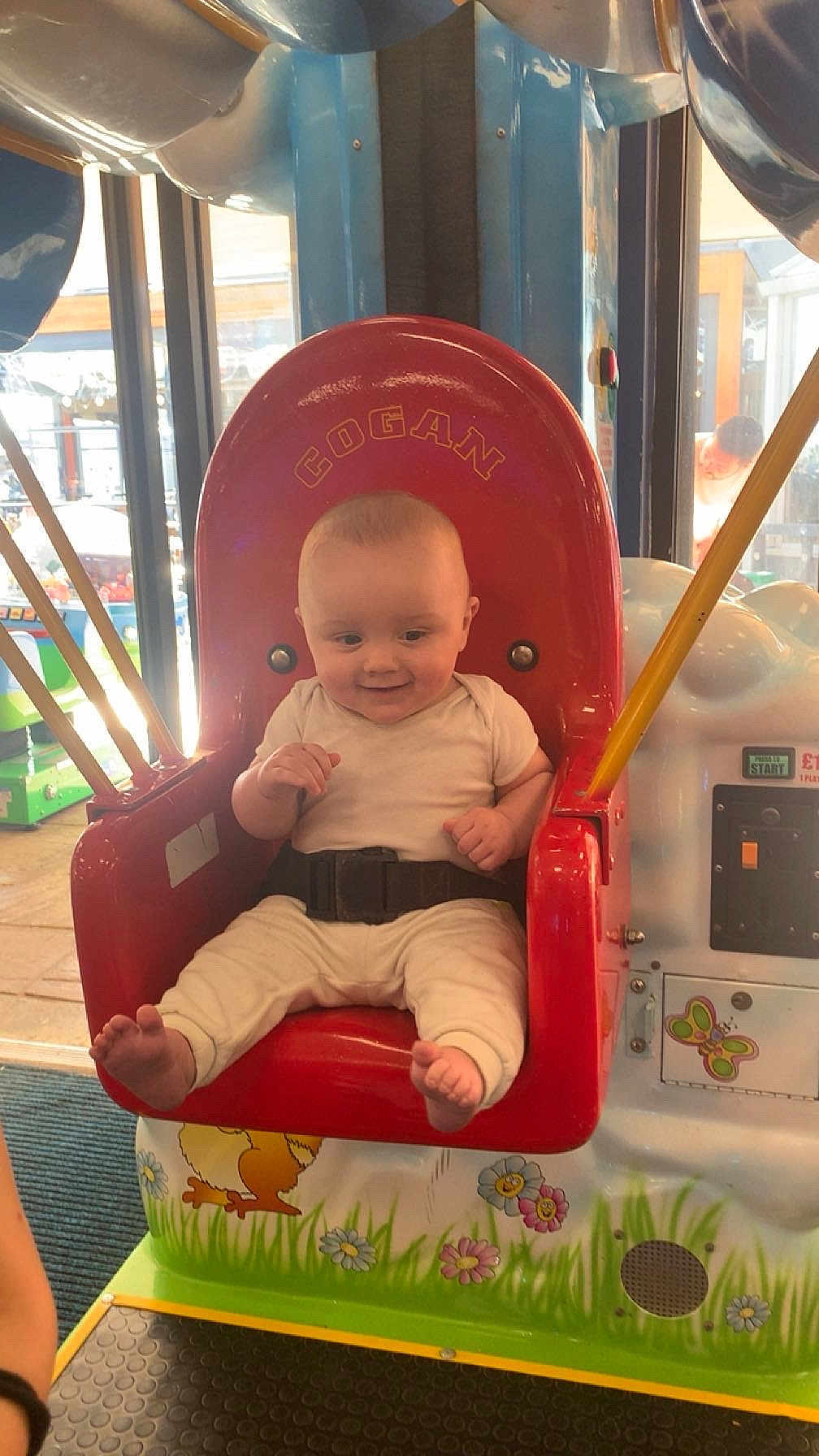 Dalton-Lee is registered to the contest to win money with this photo: baby, child, amusement_ride, seat, red, cartoon, indoor, playground, smiling, clothing, belt, feet, hands, window, daylight, floor, toy, colorful, person, happy