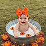 baby, child, orange_bow, metal_tub, milk_bath, pumpkins, autumn_leaves, outdoor, grass, smiling, cute, fall_theme, festive, seasonal, happy, infant, headwear, nature, decoration, playful