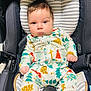 baby, infant, car_seat, onesie, festive, christmas_trees, mohawk_hair, cute, child, strapped_in, seatbelt, indoor, portrait, young_child, clothing, patterned_clothes, person, face, expression, sitting