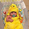 baby, child, towel, yellow, duck, pacifier, hooded_towel, infant, baby_seat, patterned_fabric, plush, cute, indoors, colorful, soft_texture, wrapped, relaxed, face, childcare, newborn