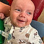 Theo joined the competition — help win amazing prizes! baby, smile, face, onesie, animal_print, giraffe, lion, tiger, hand, person, indoor, couch, red_couch, happy, closeup, infant, holding, cute, portrait, child