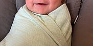 Theo joined the competition — help win amazing prizes! baby, infant, smiling, swaddled, blanket, cushion, face, head, person, happy, comfort, indoors, portrait, baby_boy, soft_texture, resting, closeup, cute, child, wrapped
