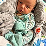 baby, blanket, dinosaur, pajamas, soft_texture, infant, cozy, patterned_clothing, cute, sleepwear, child, face, wrapped, indoor, colorful, newborn, resting, fabric, cute_expression, warm