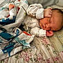 newborn, baby, sleeping, blanket, floral_quilt, infant, cozy, peaceful, cute, small_hands, patterned_clothing, indoors, resting, soft_light, closeup, portrait, toddler, child, bed, comfort