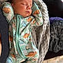 baby, sleeping, infant, onesie, dinosaur_print, blanket, soft_texture, cozy, bed, cute, peaceful, child, portrait, indoor, resting, newborn, relaxed, clothing, person, comfort