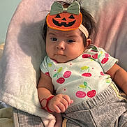 Keitlyn Ramírez joined the competition — help win amazing prizes! baby, child, infant, pumpkin_headband, cute, soft_cushion, cherry_pattern, shirt, pants, red_bracelet, indoor, portrait, expression, comfortable, seated, clothing, headwear, person, young, cozy