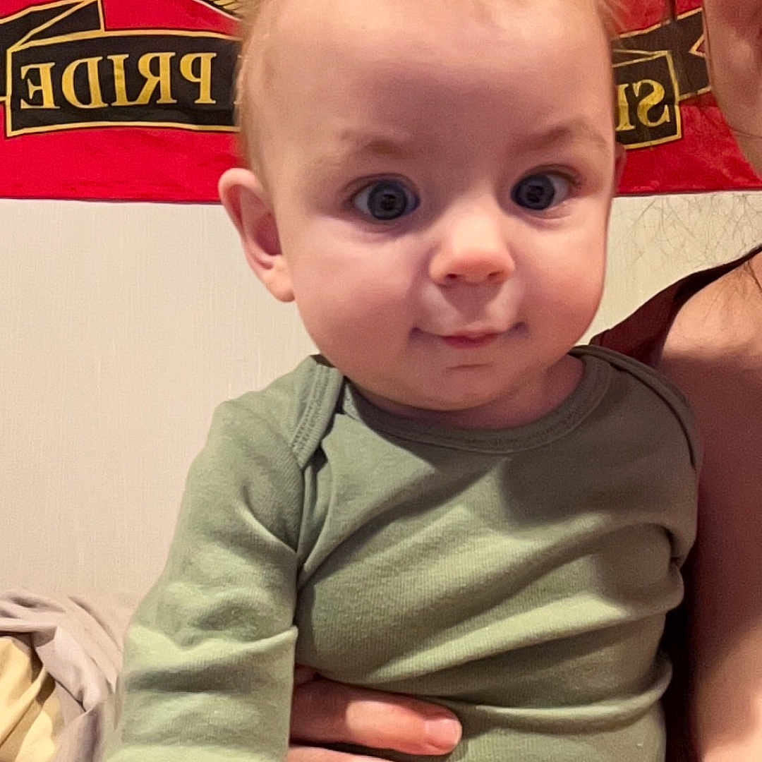 Dylan is registered to the contest to win money with this photo: baby, blonde, bodypart, clothing, face, finger, hand, happy, head, laughing, mouth, person, photography, portrait, shirt, shorts, sitting, smile, t_shirt, teeth