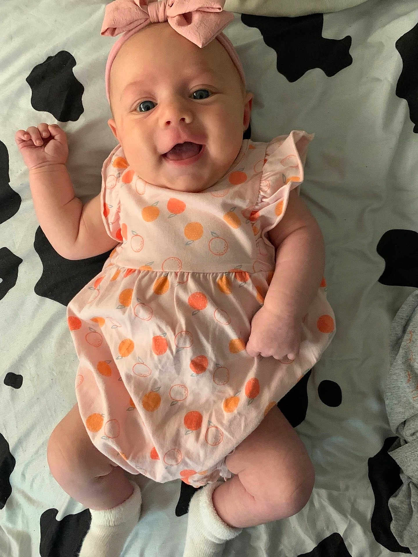 Raya joined the competition — help win amazing prizes! baby, infant, smiling, headband, dress, patterned_clothing, laying_down, blanket, white_socks, cute, happy, child, human, indoors, cheerful, closeup, skin, young, pink, orange
