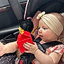 baby, infant, child, car_seat, headband, bow, happy_meal_box, red_box, car_interior, seatbelt, pink_clothing, floral_pattern, hand, foot, curious, portrait, sitting, safety_harness, cute, young_child
