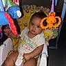 baby, child, infant, sitting, activity_center, baby_chair, toy, octopus_toy, colorful, portrait, indoors, playtime, white_shirt, dark_hair, wide_eyes, face, hands, legs, fabric, flash_photography