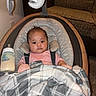 baby, infant, child, portrait, bouncer, blanket, bottle, feeding_bottle, pink_clothing, seated, indoors, staircase, carpet, furniture, wide_eyes, dark_hair, face, home, cozy, photography