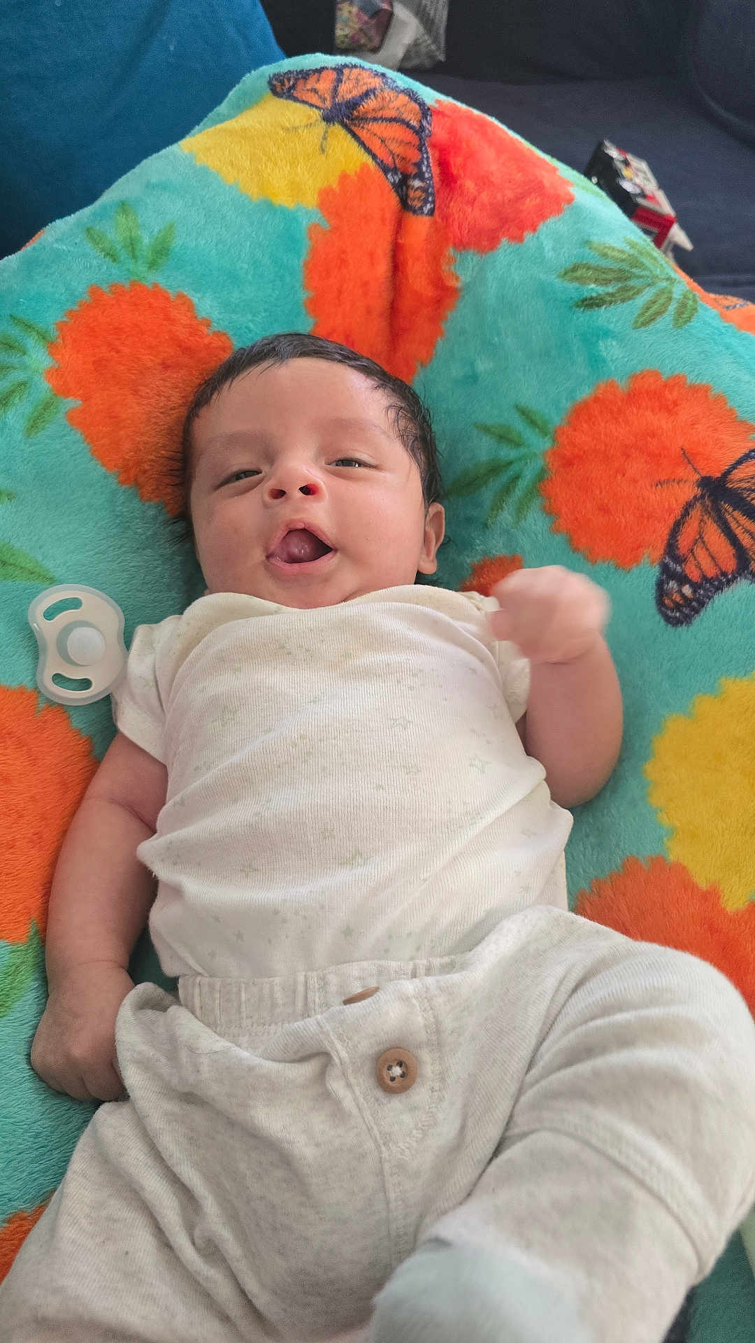 Julian joined the competition — help win amazing prizes! baby, infant, blanket, pineapple_pattern, butterfly_pattern, white_clothing, pacifier, lying_down, cute, smiling, indoors, soft_toy, child, face, head, hand, legs, fabric, colorful, comfortable