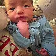 Aleia Rose is registered to the contest to win money with this photo: baby, infant, blue_onesie, hand, face, curious, portrait, person, pillow, pattern, heart, tower, dog_print, shirt, clothing, indoor, closeup, expression, holding, resting