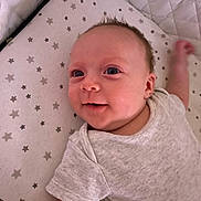 Ellie is registered to the contest to win money with this photo: baby, infant, smiling, onesie, lying_down, star_pattern, mattress, cute, child, young, face, skin, arm, happy, indoors, portrait, person, head, expression, baby_clothes