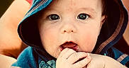 Hudson joined the competition — help win amazing prizes! baby, child, hood, blue_clothing, hands, fingers, face, eyes, adult_hand, tattoo, ring, portrait, cute, infant, skin, expression, closeup, person, holding, outdoor
