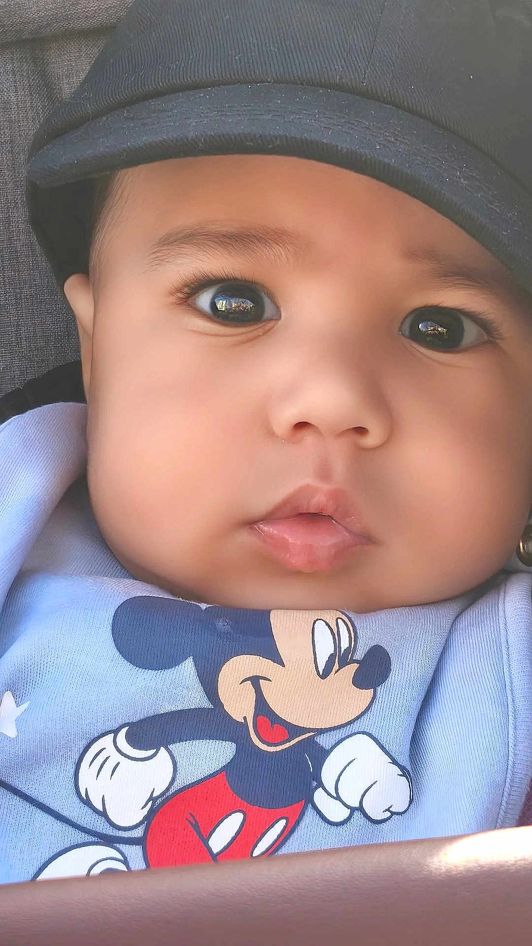 Jayden a rejoint le concours — aidez-le/la à gagner de superbes lots ! baby, infant, face, hat, cap, big_eyes, long_eyelashes, chubby_cheeks, lips, mickey_mouse, cartoon, onesie, clothing, closeup, portrait, cute, curious_expression, car_seat, soft_lighting, eye_reflection