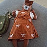 Zia joined the competition — help win amazing prizes! baby, infant, child, pacifier, bow, headband, dress, brown_clothing, white_sleeves, lying_down, couch, handbag, fashion, portrait, indoor, carpet, furniture, feet, baby_doll, photography