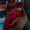 arm, baby, bow, child, closeup, comfort, couch, cute, fabric, hand, holding, indoors, infant, person, red_clothing, rest, skin, sleeping, soft, tenderness
