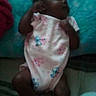baby, blanket, blur, cartoon_print, child, clothing, cozy, cute, dark_skin, fabric, footwear, indoor, infant, lying_down, onesie, person, resting, sleeping, socks, soft_texture