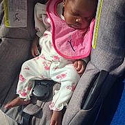 Zia is registered to the contest to win money with this photo: baby, child, sleeping, car_seat, pink_bib, floral_pajamas, infant, seatbelt, safety_warning, clothing, person, cute, resting, indoors, portrait, newborn, toddler, babywearing, seat, head