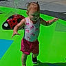 Winter is registered to the contest to win money with this photo: child, toddler, outdoor, splash_pad, water_play, ladybug, sprinkler, summer, sunlight, swimsuit, shorts, shoes, walking, smiling, portrait, playground, colorful, green, red, recreation