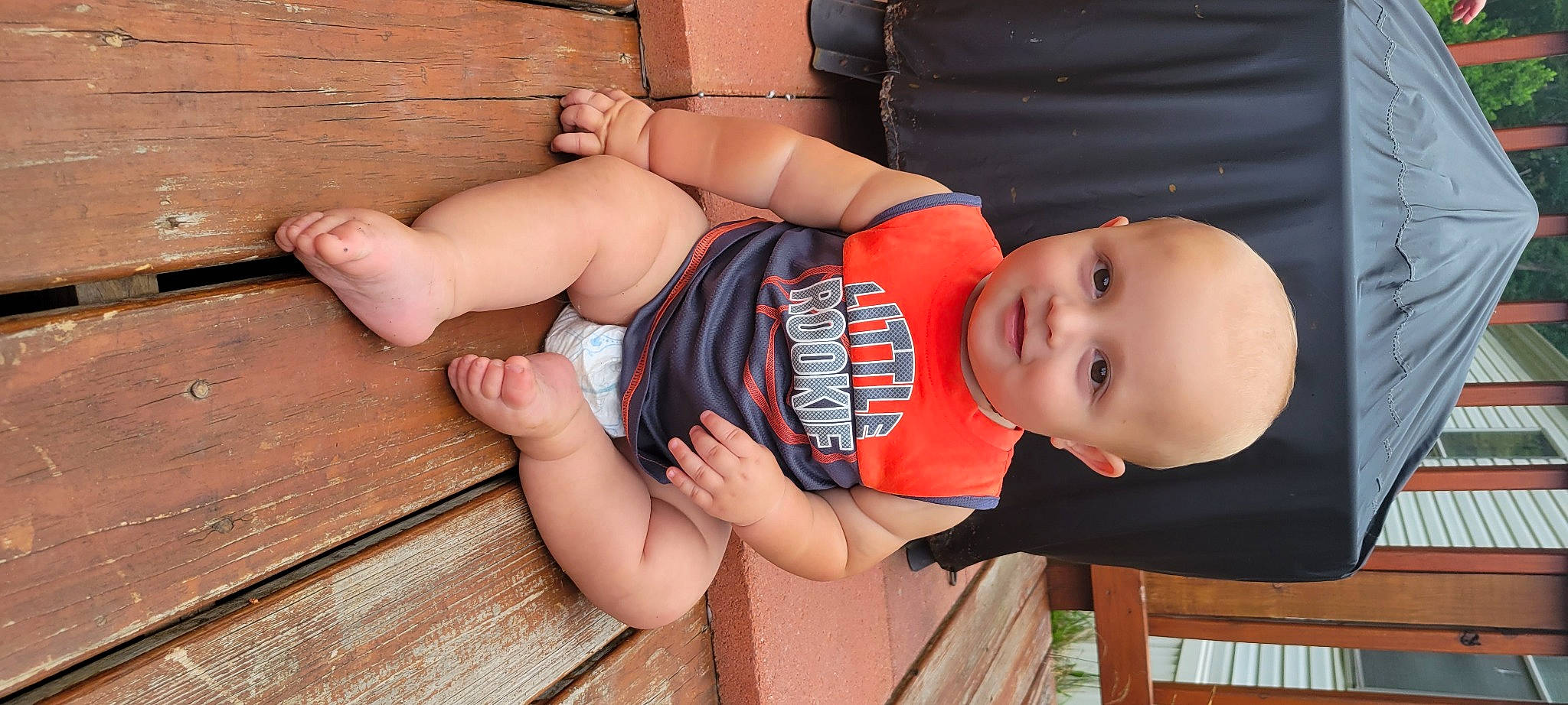 Tre is registered to the contest to win money with this photo: arm, baby_toddler_clothing, elbow, finger, glasses, hand, human_body, joint, joy, knee, leg, leisure, mouth, muscle, orange, person, plant, skin, sunglasses, thigh