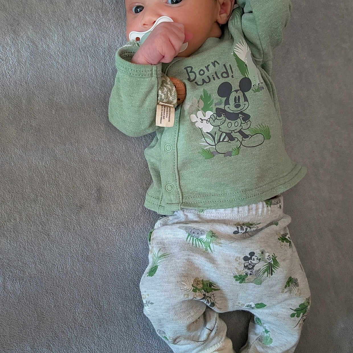 Maddox joined the competition — help win amazing prizes! adorable, baby, blanket, child, curious_eyes, cute, green_clothing, indoor, infant, lying_down, mickey_mouse, pacifier, patterned_pants, portrait, relaxed, sleepwear, small_hands, socks, soft_texture, young