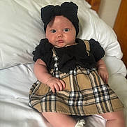 Eden-Rose is registered to the contest to win money with this photo: baby, infant, child, bed, pillow, dress, plaid, headband, bow, white, sock, cute, portrait, indoors, furniture, wood, curious, soft, skin, resting