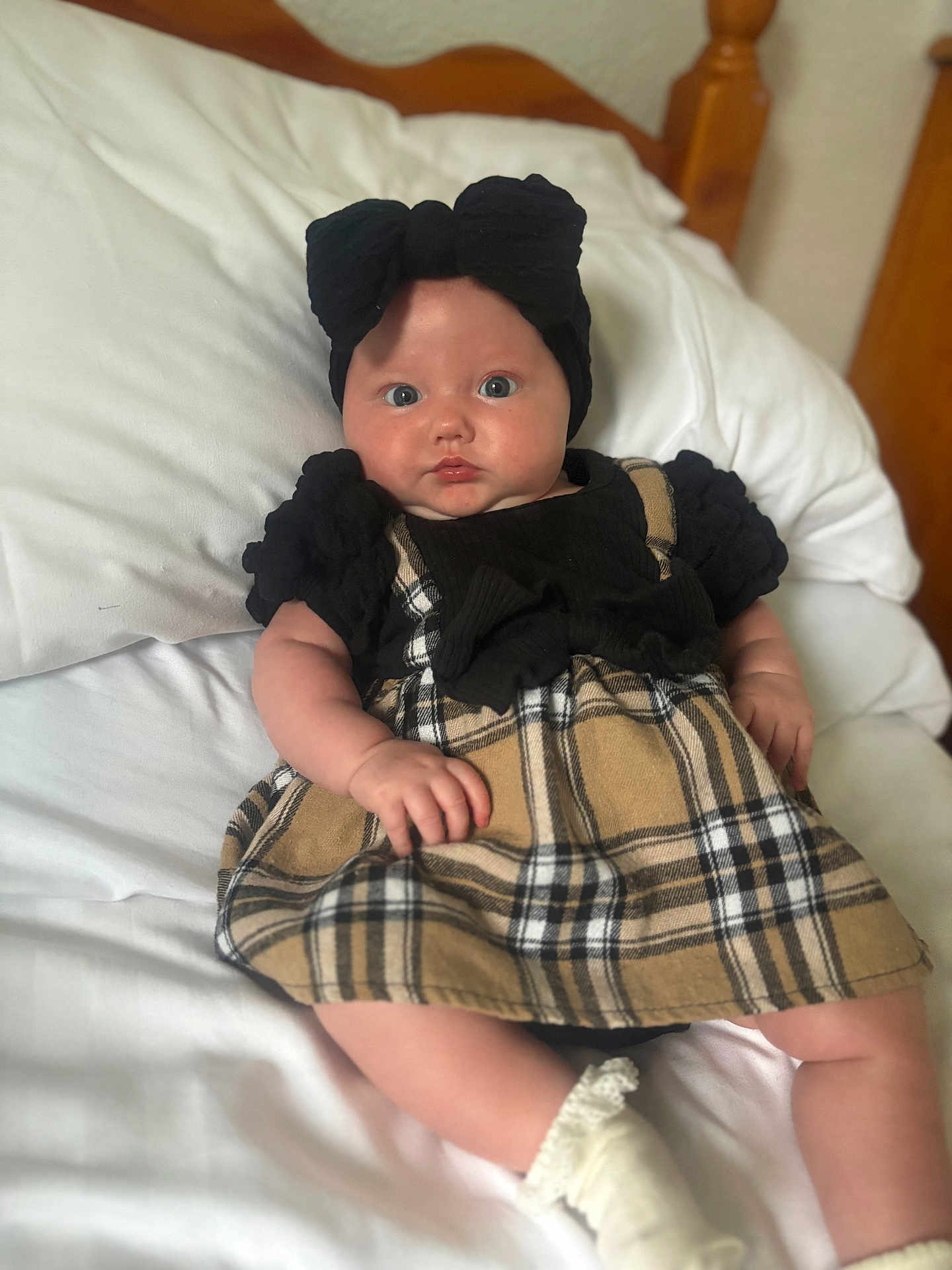 Eden-Rose is registered to the contest to win money with this photo: baby, infant, child, bed, pillow, dress, plaid, headband, bow, white, sock, cute, portrait, indoors, furniture, wood, curious, soft, skin, resting