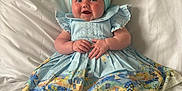 Eden-Rose is registered to the contest to win money with this photo: baby, child, blue_dress, headband, bow, smiling, happy, sitting, bed, white_bedspread, infant, cute, portrait, indoor, clothing, sock, hands, face, person, young